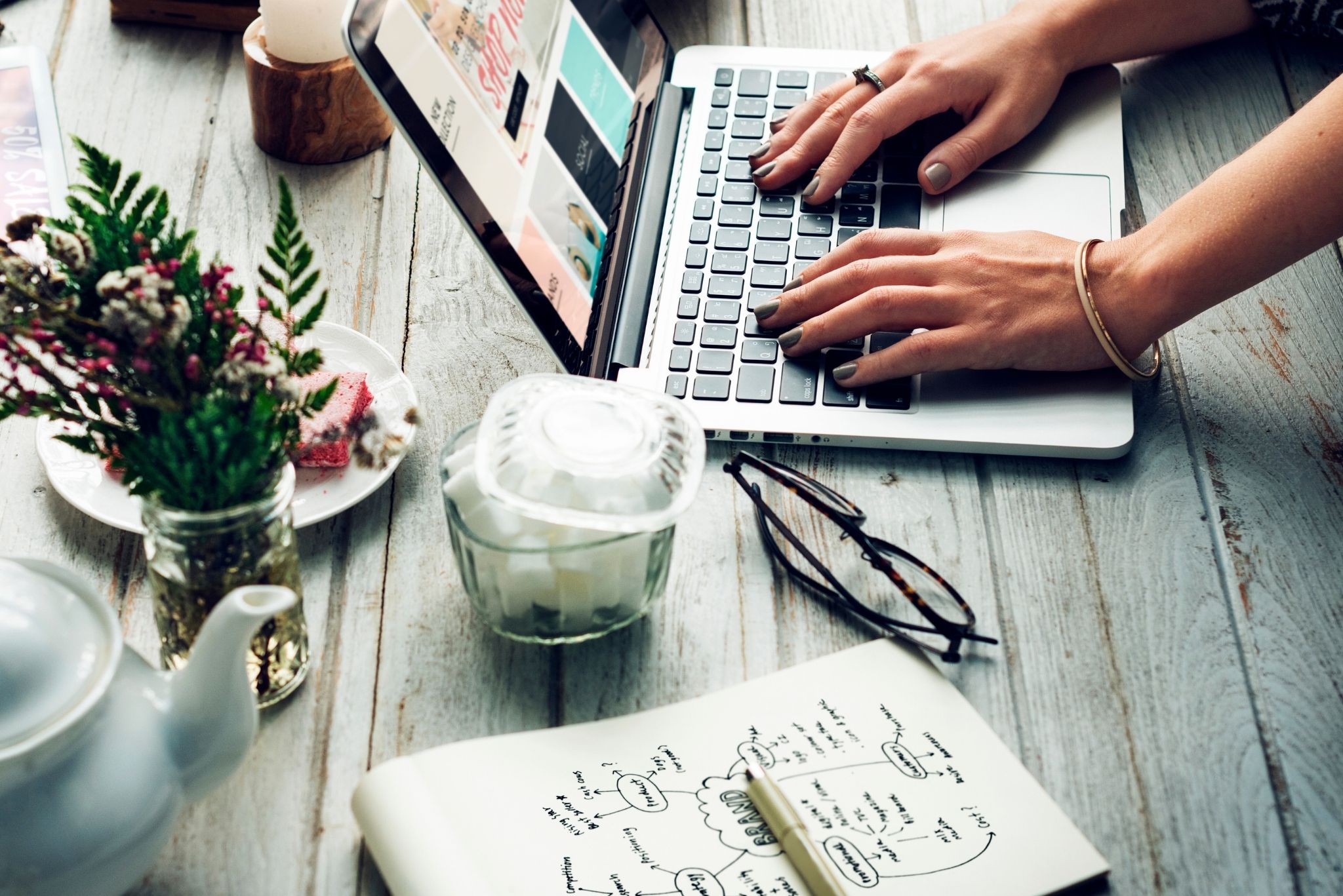 Content creation workspace with laptop, notes, and tea — representing branded marketing solutions in Brisbane including SEO copywriting and blog writing.