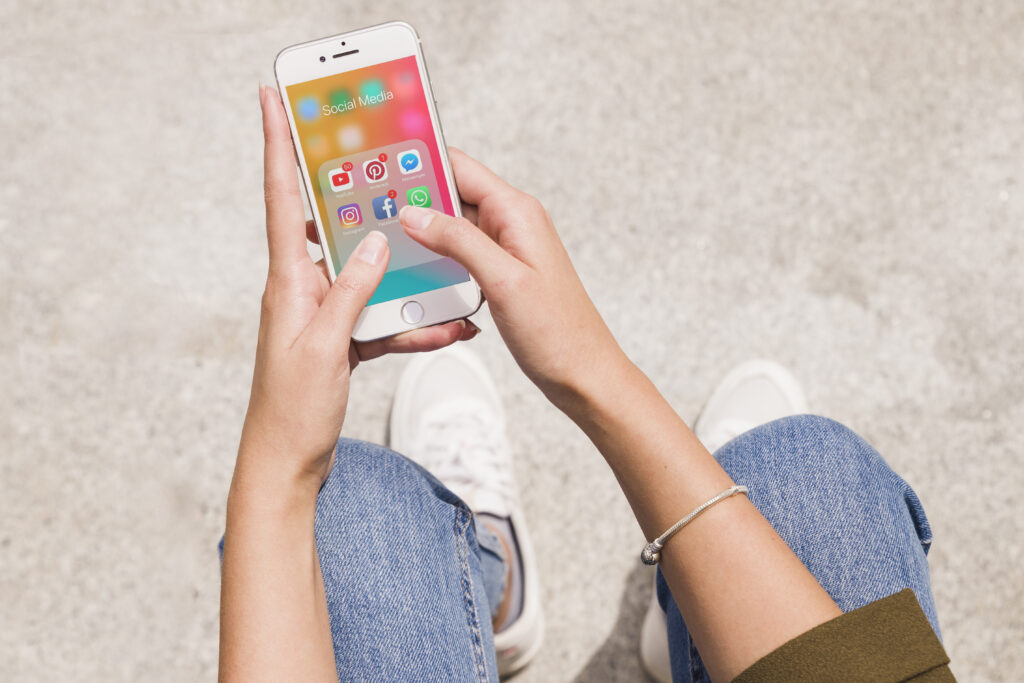 Hands holding smartphone with social media apps open — part of branded marketing solutions Brisbane businesses rely on for digital presence and consistency.